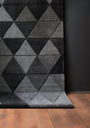 A modern geometric-patterned gray hand tufted carpet made of wool and silk/viscose, displayed in an interior setting with wooden flooring.