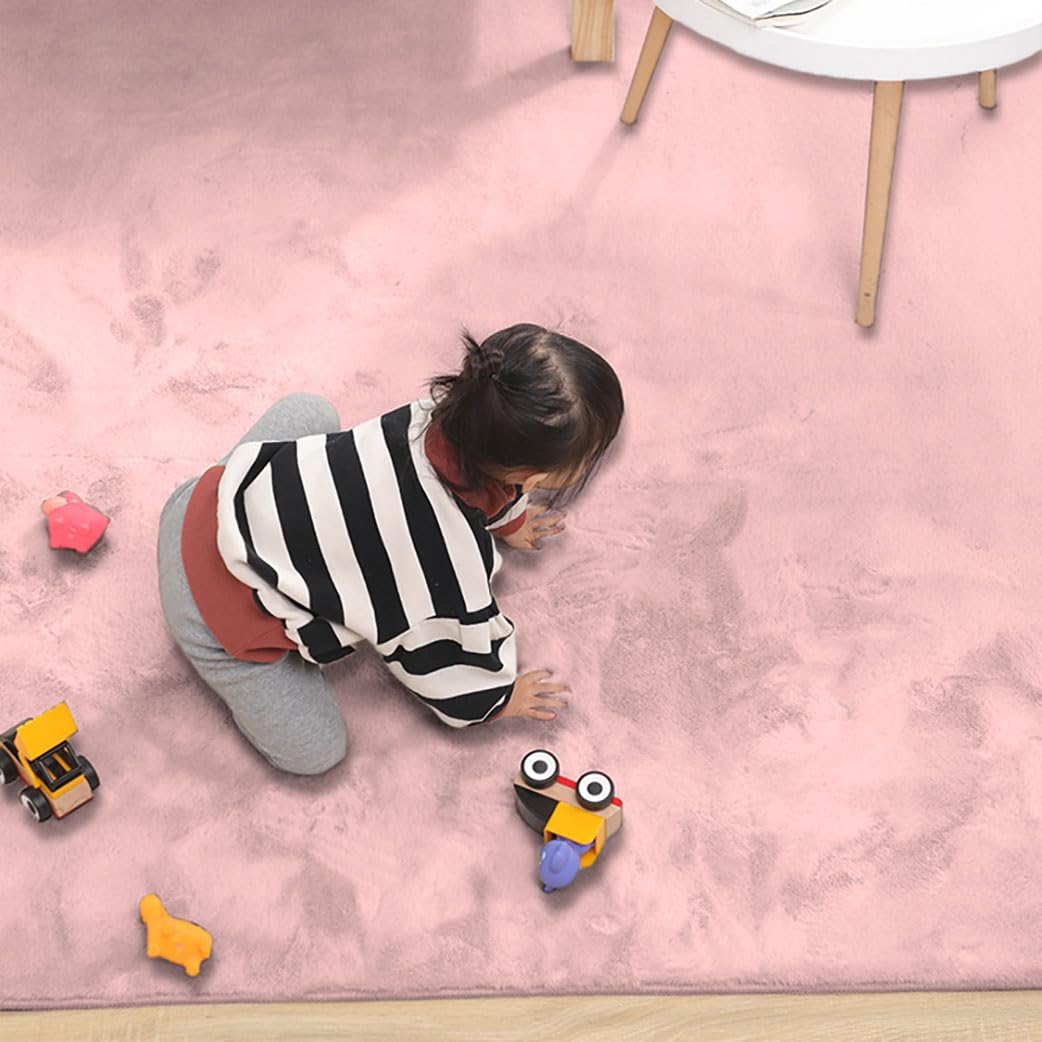 Child playing on a pink rabbit fur carpet with toys