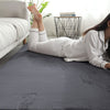 Person lying on a dark gray rabbit fur carpet in a room