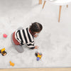 Child playing on a soft white rabbit fur carpet with toys