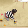 Child playing on a camel beige rabbit fur carpet with toys