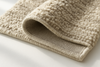 Close-up of the underside of a luxury rug showing dense wool pile with canvas backing — focus on quality texture, neat edges, and durability — photographed on a bright, clean surface with soft daylight, minimalist styling to emphasize craftsmanship.