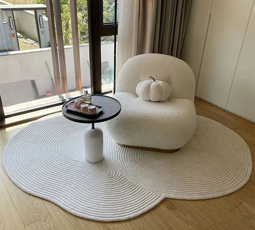 Cloudform irregular hand tufted rug in soft white with organic shape styled under a reading chair in sunlit room