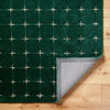 Corner fold showing the thickness and tufted texture of green rug.