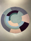 Geometric circle wool rug in peach, lavender grey, and green accents