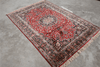 Full view of Persian heritage hand-knotted rug with deep ruby red field, intricate navy floral border and cream fringe 