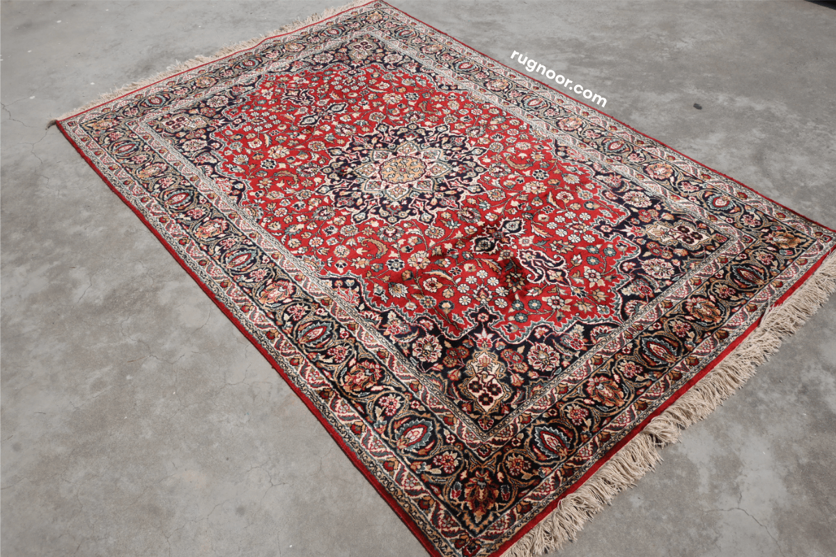 Full view of Persian heritage hand-knotted rug with deep ruby red field, intricate navy floral border and cream fringe 