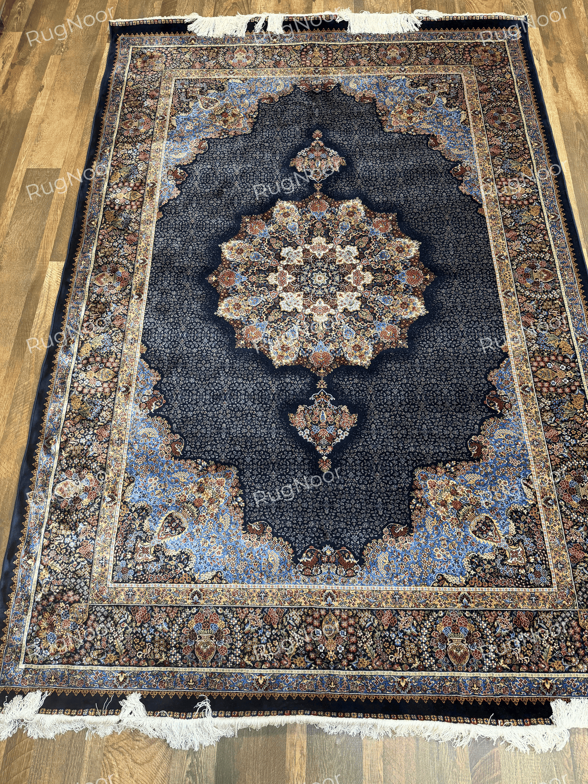 Full view of a navy blue traditional carpet with an ornate floral medallion, multicolour borders, and fringed edges by RugNoor