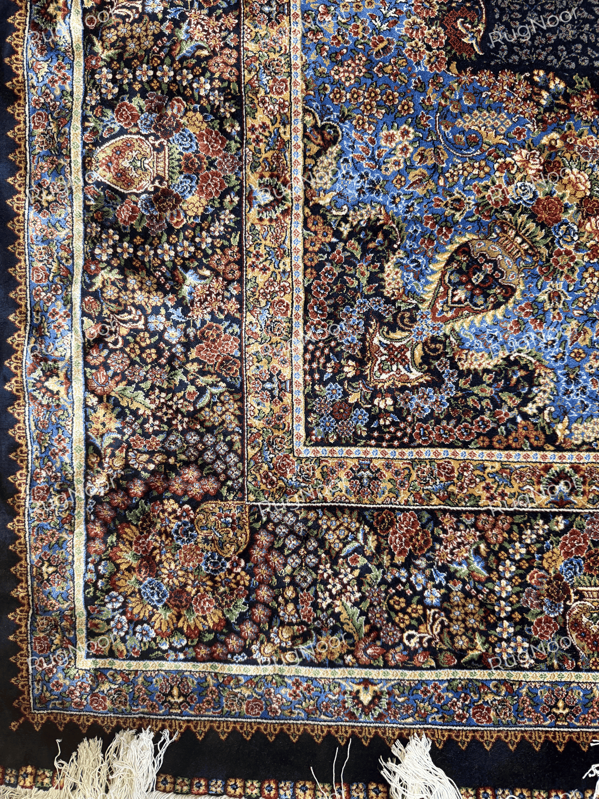 Close-up of the carpet's intricate floral border in cream, rust, gold, and blue with fringed edging by RugNoor