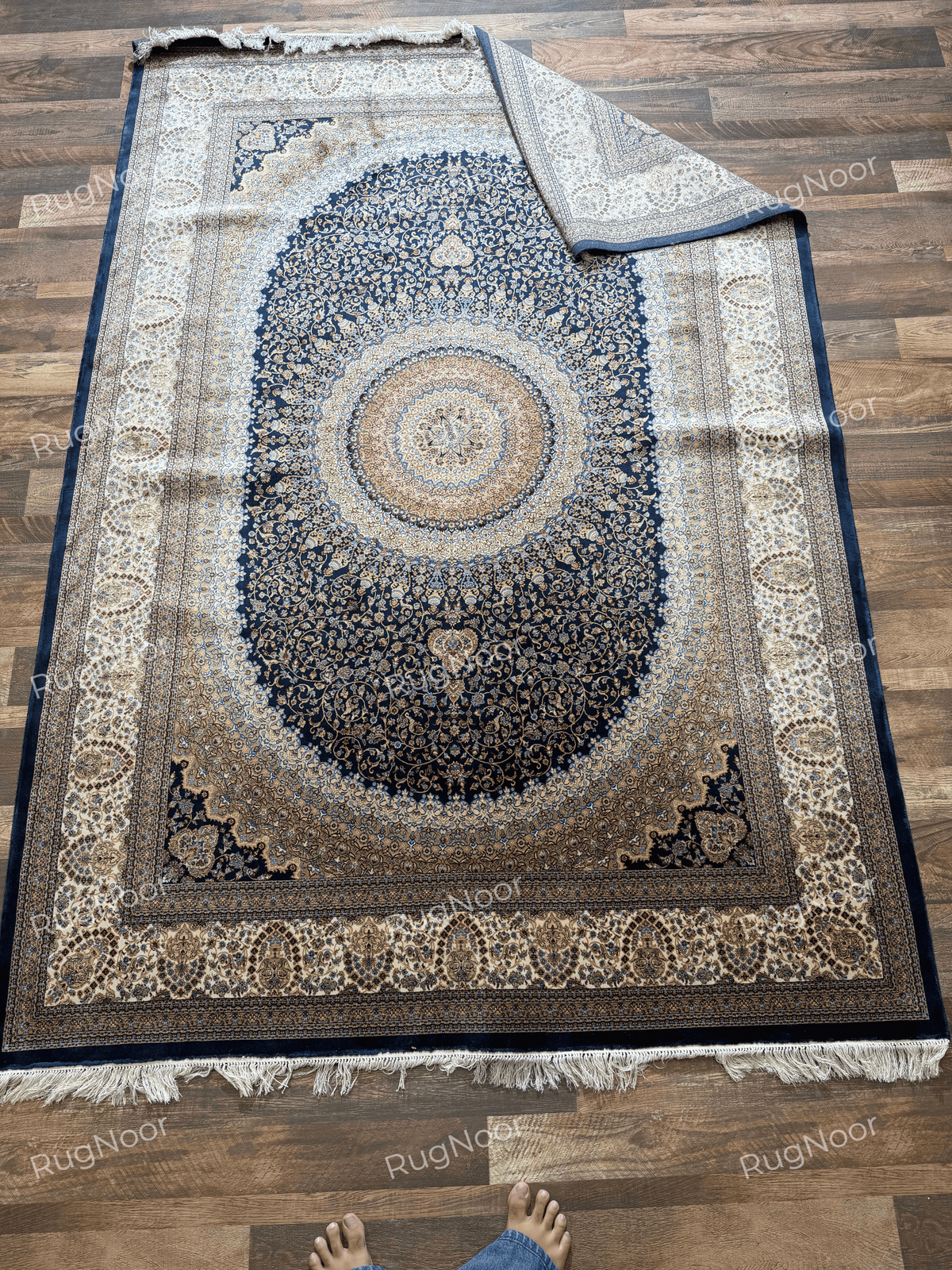 Shabafruz rug with one corner folded diagonally over the main design, revealing its light patterned underside.