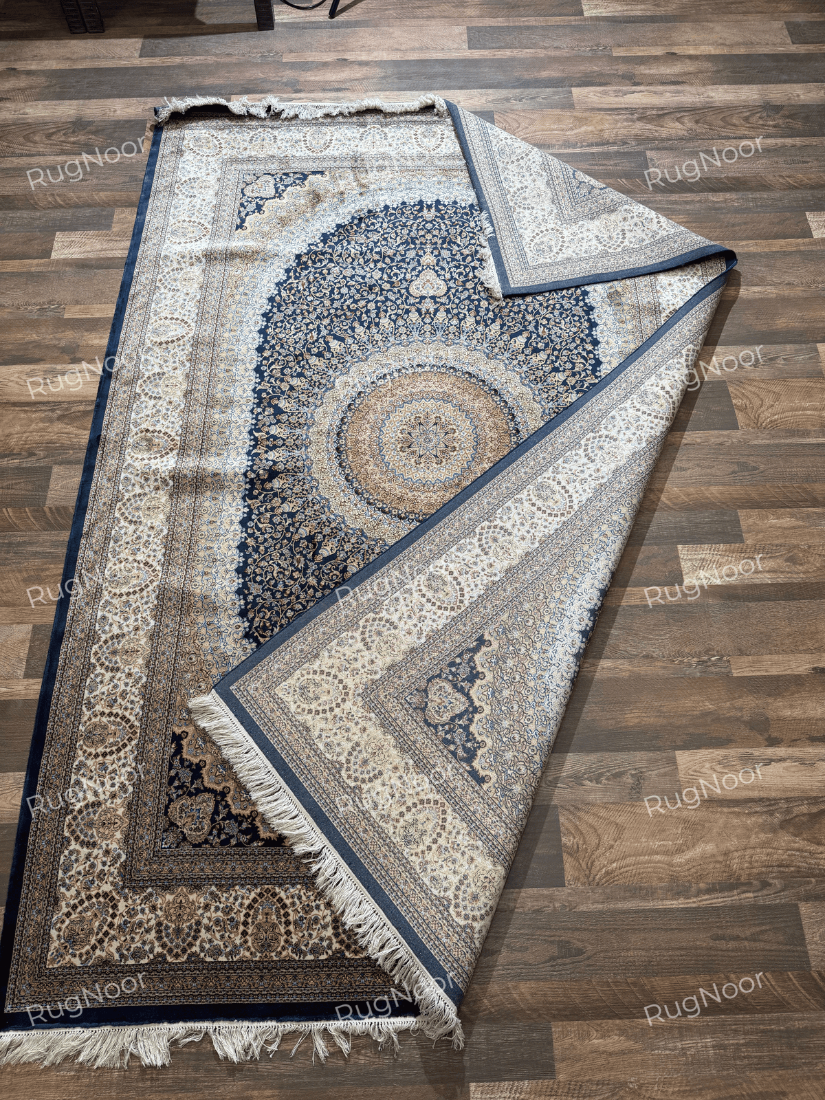 Shabafruz rug folded back across the centre, exposing the pale underside and decorative border.