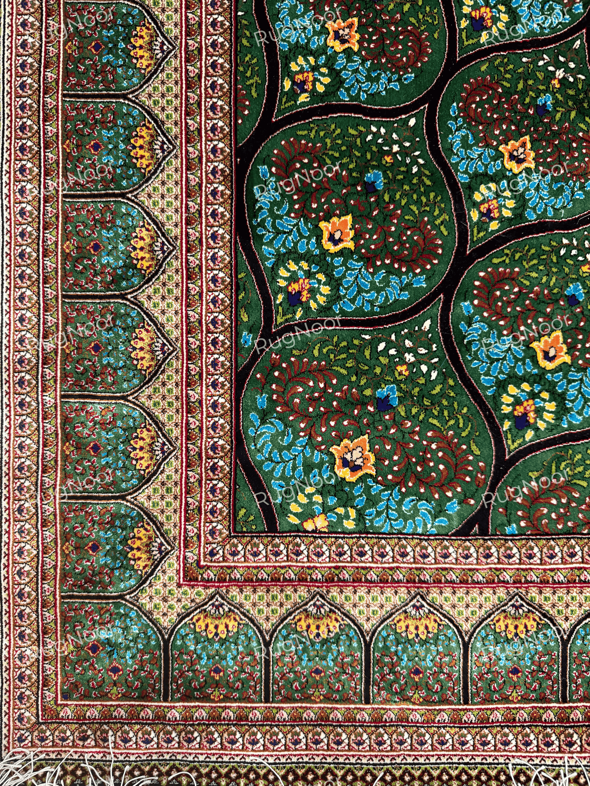 Detailed view of the Tawus carpet's repeating teardrop motifs filled with colourful floral designs.