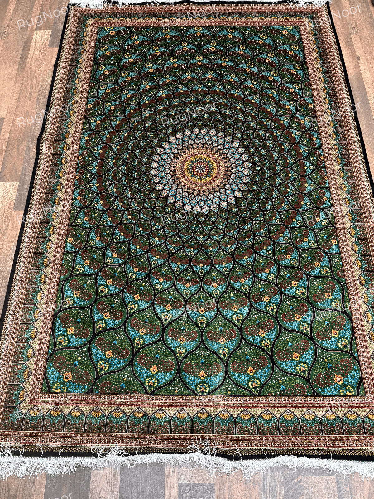 Full view of the Tawus green carpet with a central medallion and repeating teardrop-shaped floral panels.