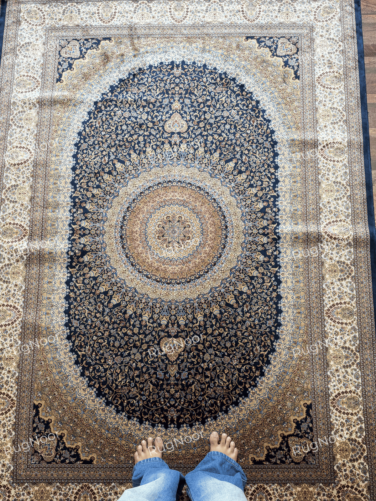 View looking down at the Shabafruz rug’s central circular medallion and dense navy floral pattern.