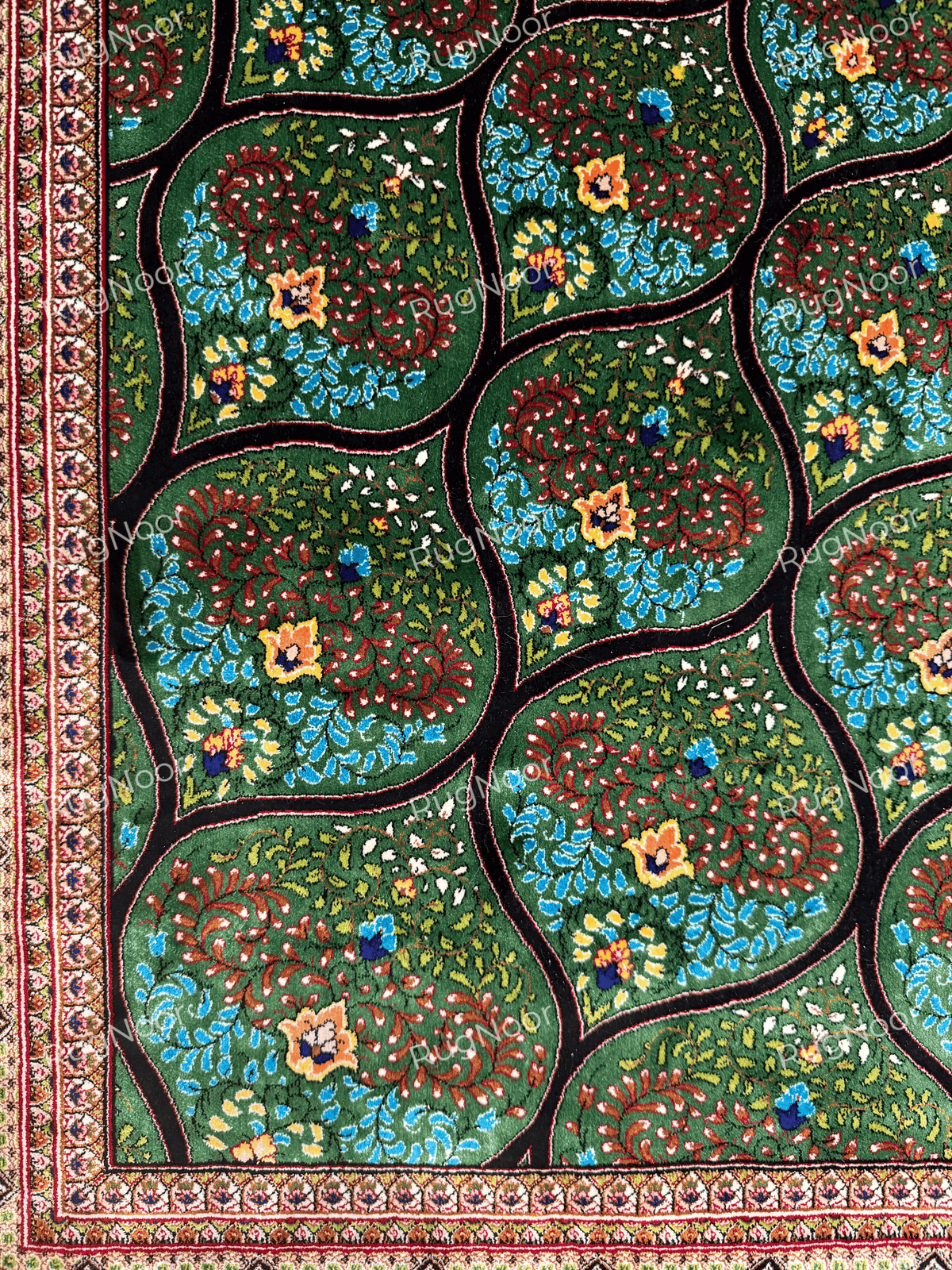 Detailed view of repeating teardrop-shaped motifs and colourful flowers across the green Tawus carpet.