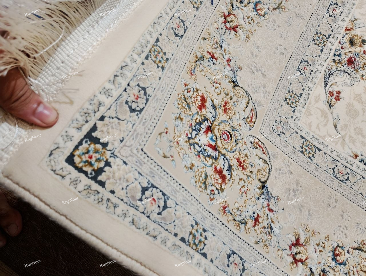 Close-up of Mehravi's ivory decorative border with intricate floral motifs in dusty blue, rust, muted red and gold beside the cream patterned field.