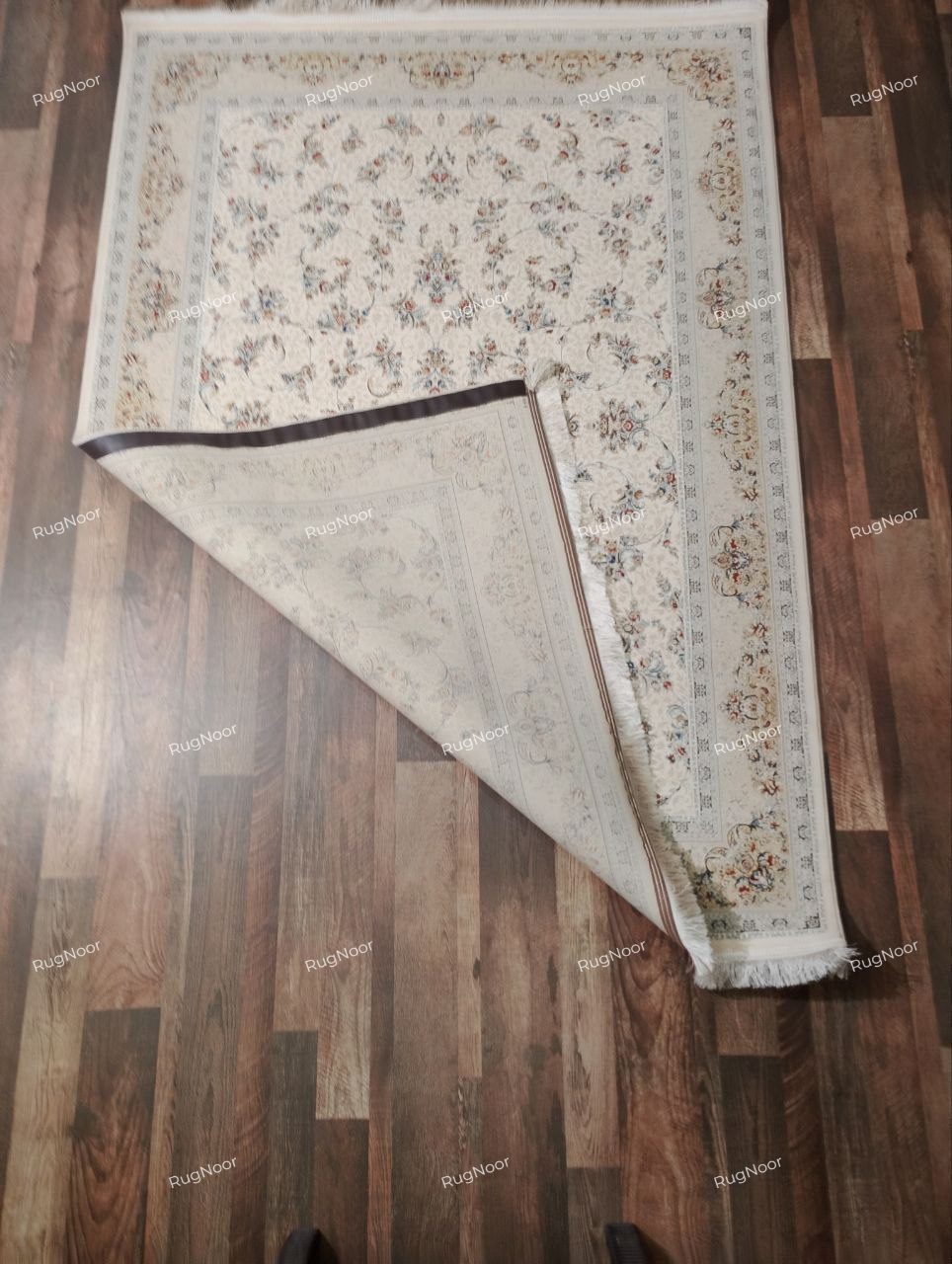 Folded corner of the Mehravi 5x7 traditional ivory floral carpet showing the reverse side, edge finish, fringe and patterned surface.