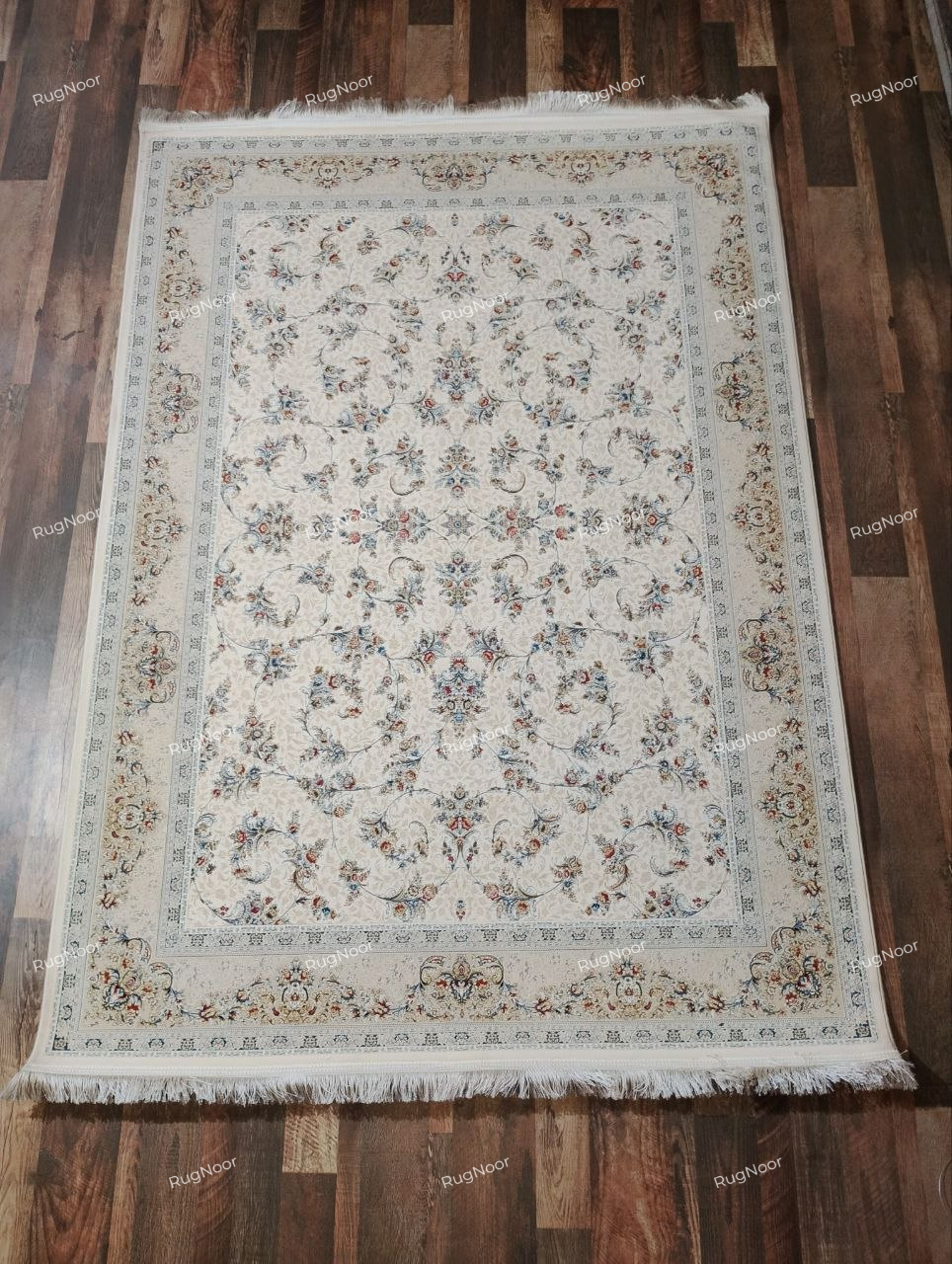 Mehravi 5x7 traditional floral carpet with an ivory and cream field, delicate blue, rust and gold motifs, an ornate border, and ivory fringe.