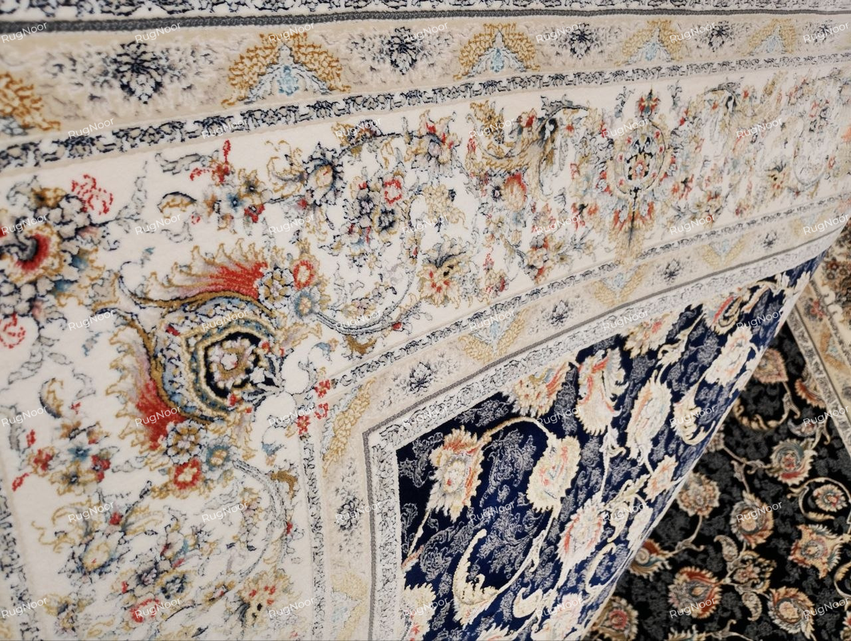 Detailed view of the Zarniva carpet's ivory ornamental border with delicate floral motifs in rust, gold, pale blue and navy beside the dark blue patterned field.
Copy alt text