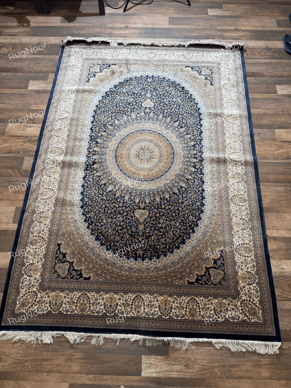Full Shabafruz rug laid flat, with an oval navy floral field, circular centre medallion, and wide ivory border.