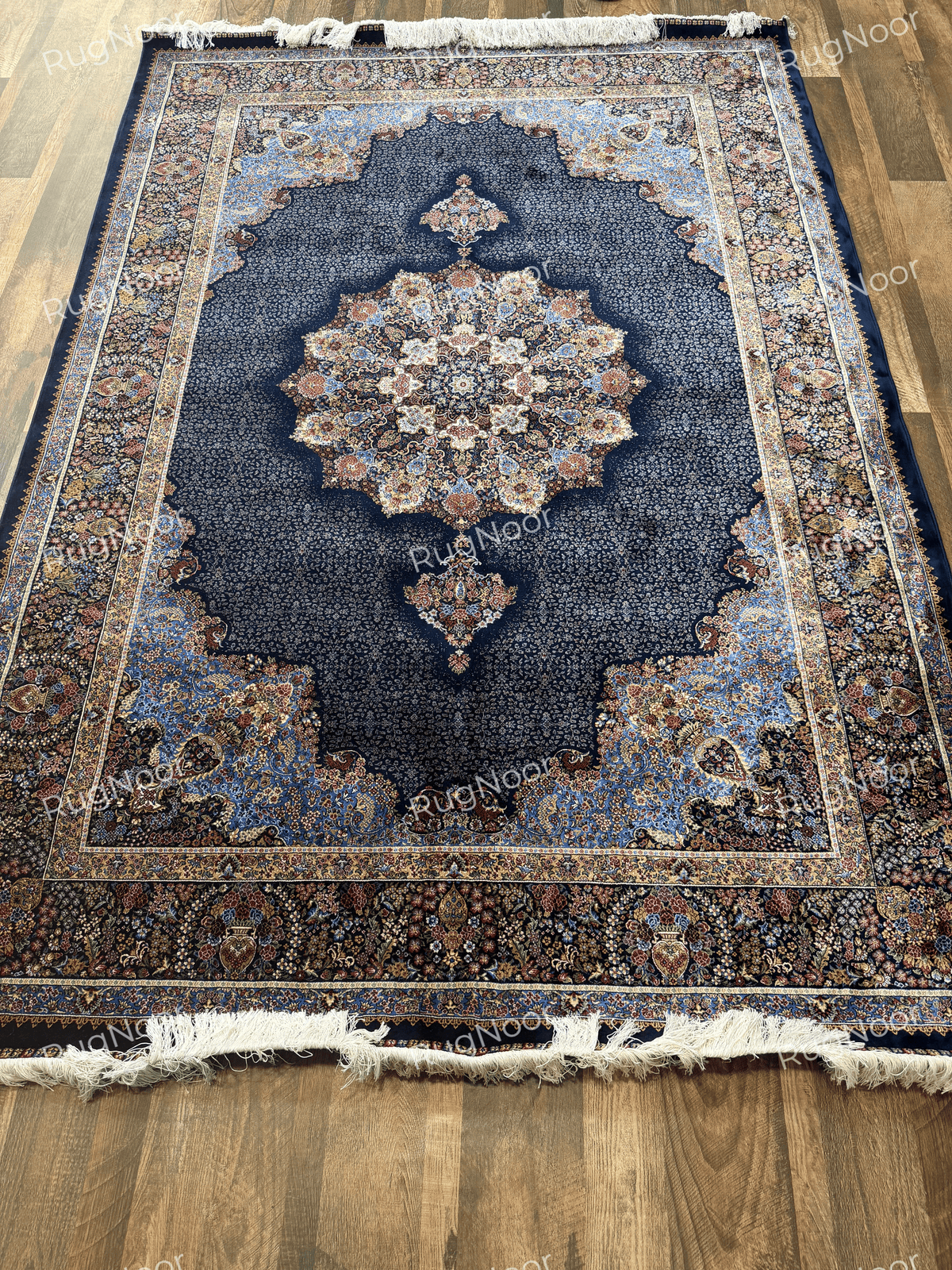full view of the navy blue carpet showing its central medallion, decorative borders, and fringed edges by RugNoor