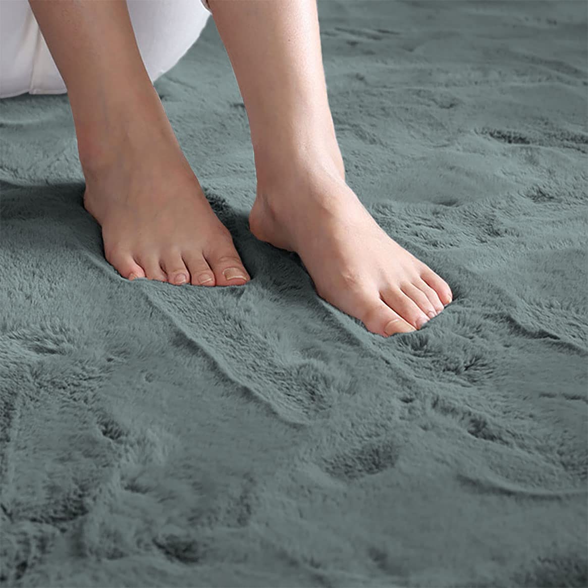 Feet stepping on a grey rabbit fur carpet