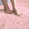Person standing on a soft pink rabbit fur carpet with a close-up of their feet