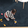 Child playing with toys on a dark blue rabbit fur carpet