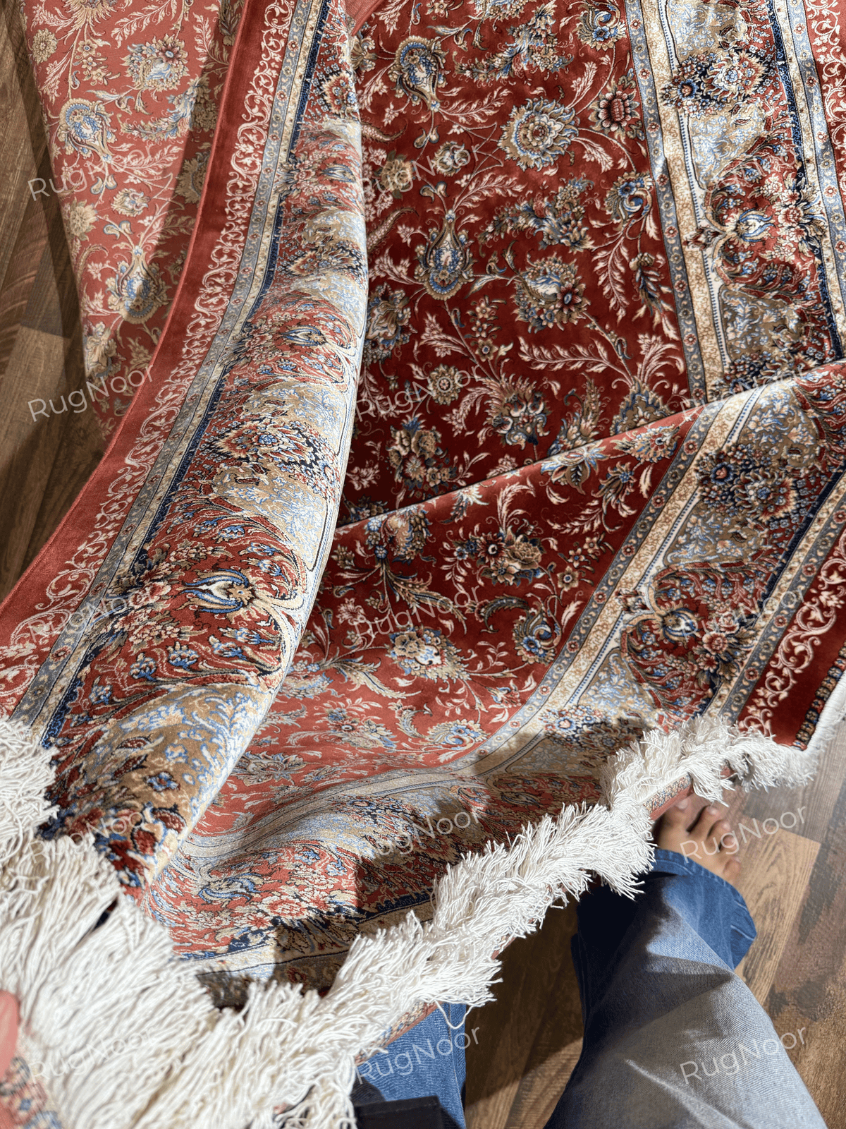 Atashgul rug gathered in folds, showing its flexible surface, floral pattern, and contrasting borders.