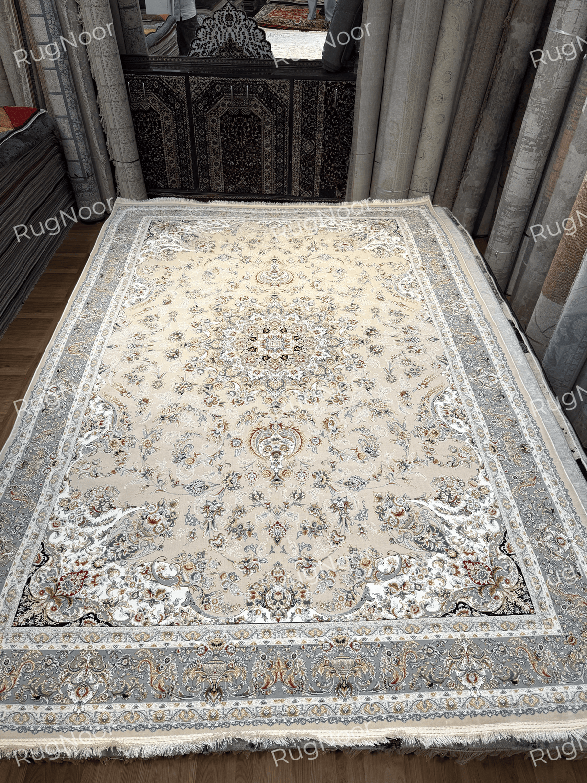 Full view of Urkeed showing its beige floral design, grey border and fringed short edge, RugNoor.