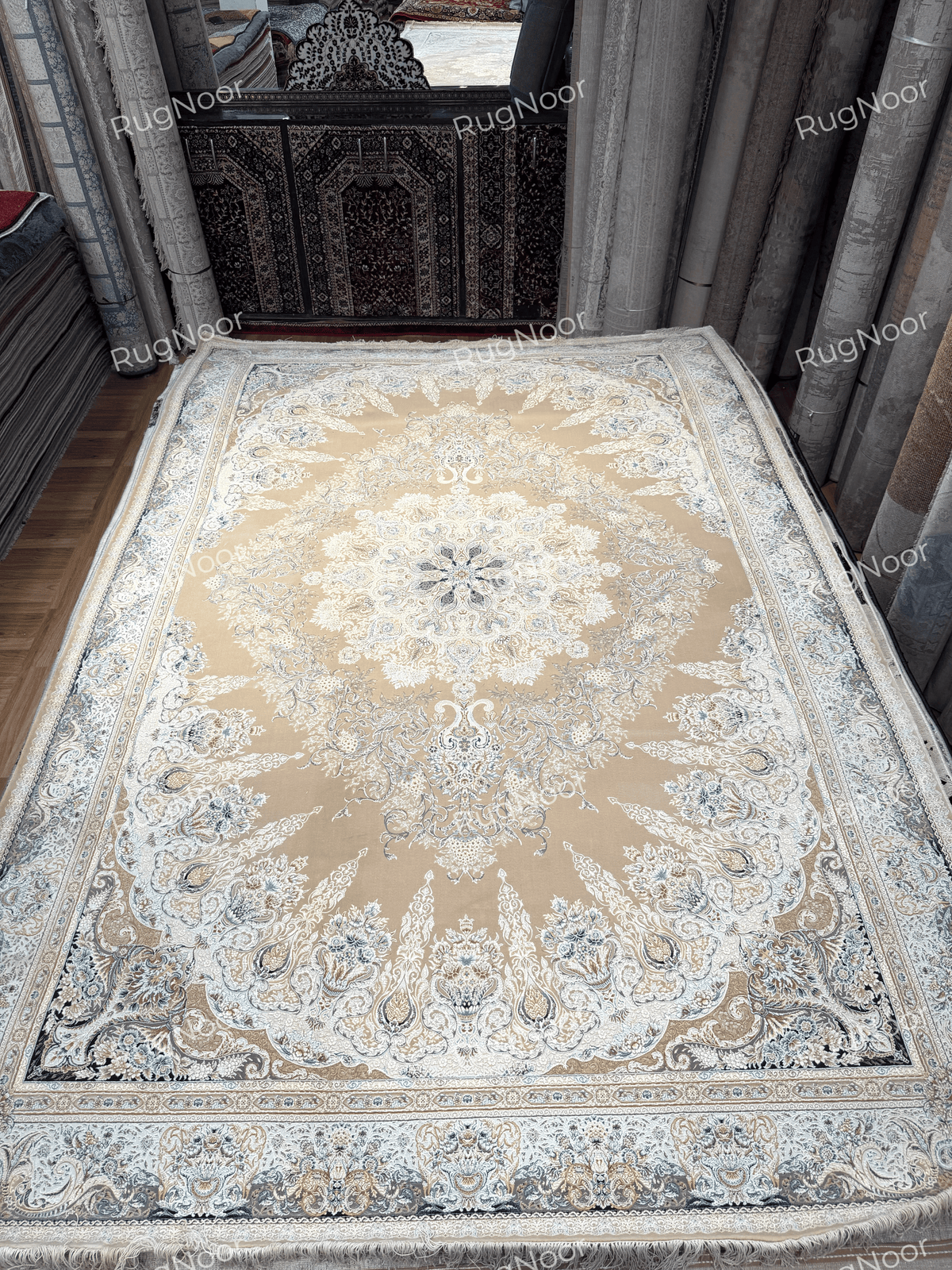 Full 6x9 Warda carpet displayed in a showroom, featuring a beige centre, ornate floral medallion and ivory-grey border, RugNoor.