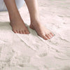 Feet standing on a soft, ivory rabbit fur carpet