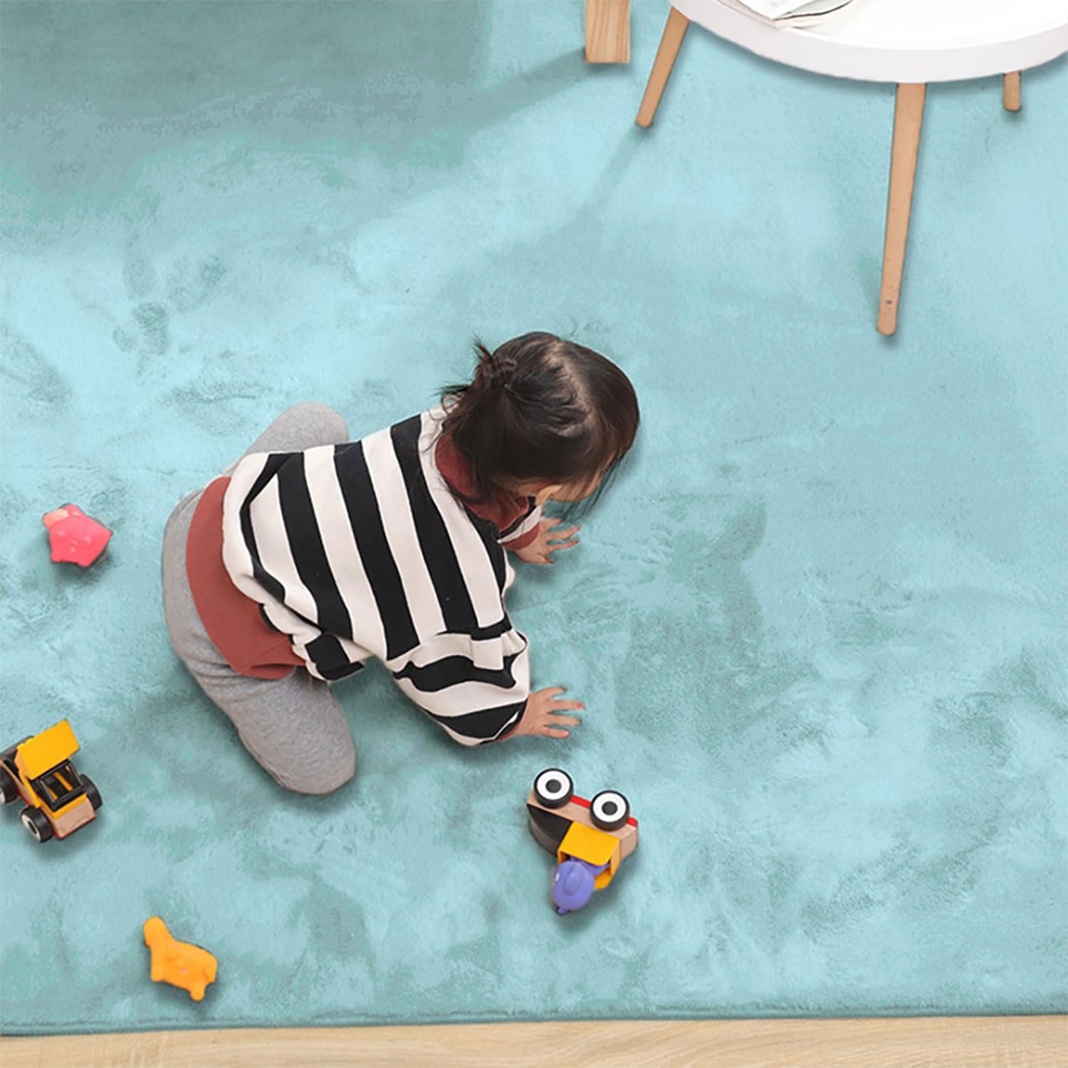 Child playing with toys on a light blue rabbit fur carpet