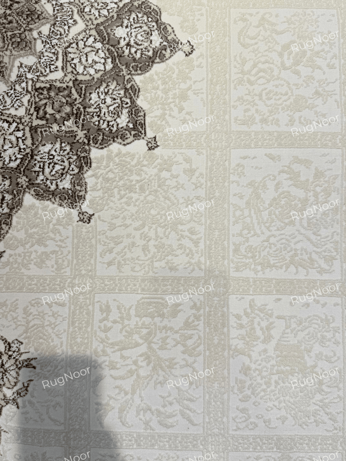 Ornate brown-grey floral border framing the ivory field of the Parichehr carpet, RugNoor.