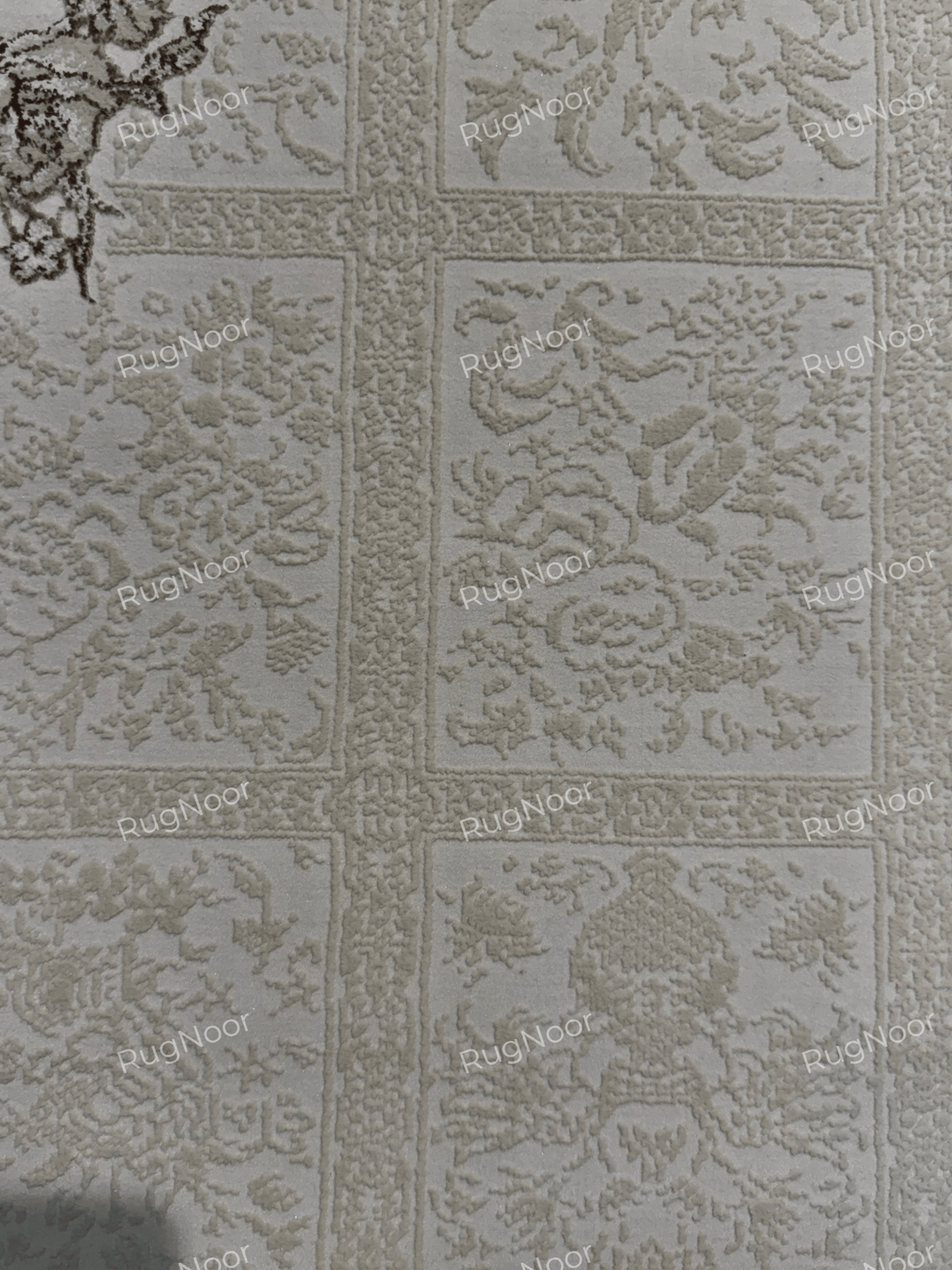 Close-up of the ivory patchwork field with subtle ornamental motifs on the Parichehr carpet, RugNoor.