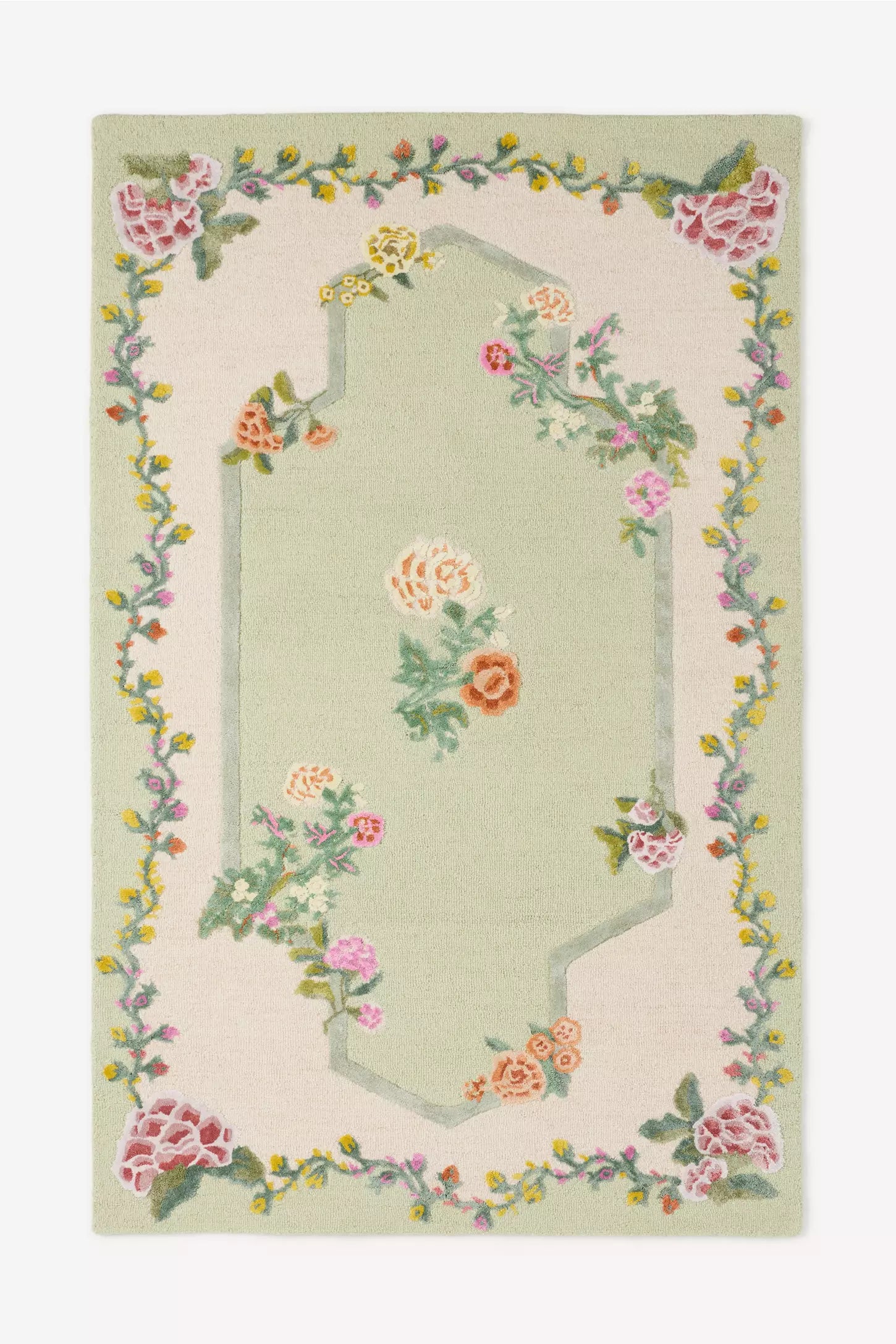 A rectangular area rug with a light sage green center and a cream border, decorated with a floral vine pattern in pink, peach, yellow, and green.