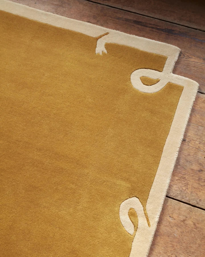 Close-up of the Astera hand tufted wool rug showcasing its sculpted border and curled corner motif.