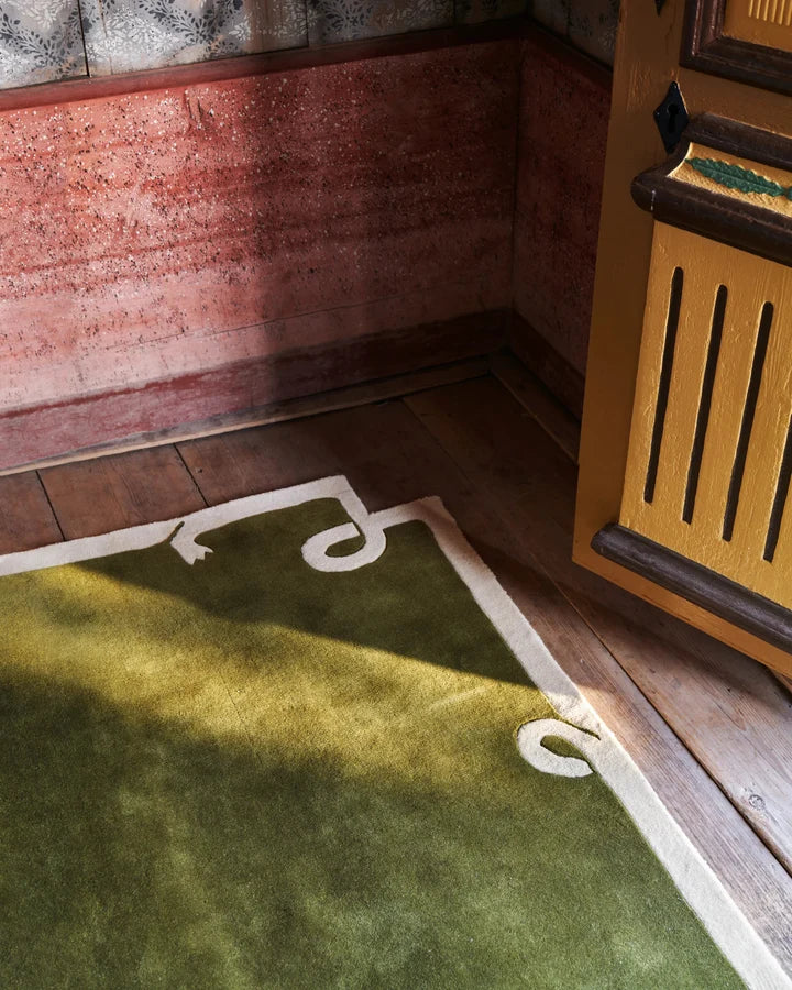 Close up of Olive green hand tufted wool rug with a sculpted border styled.