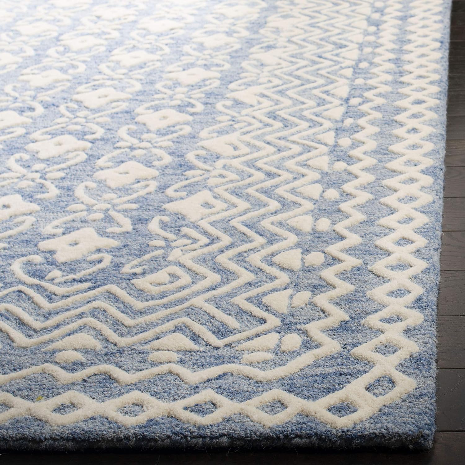 Close-up of the Aveline hand tufted wool rug highlighting its raised ivory geometric border and powder blue background.