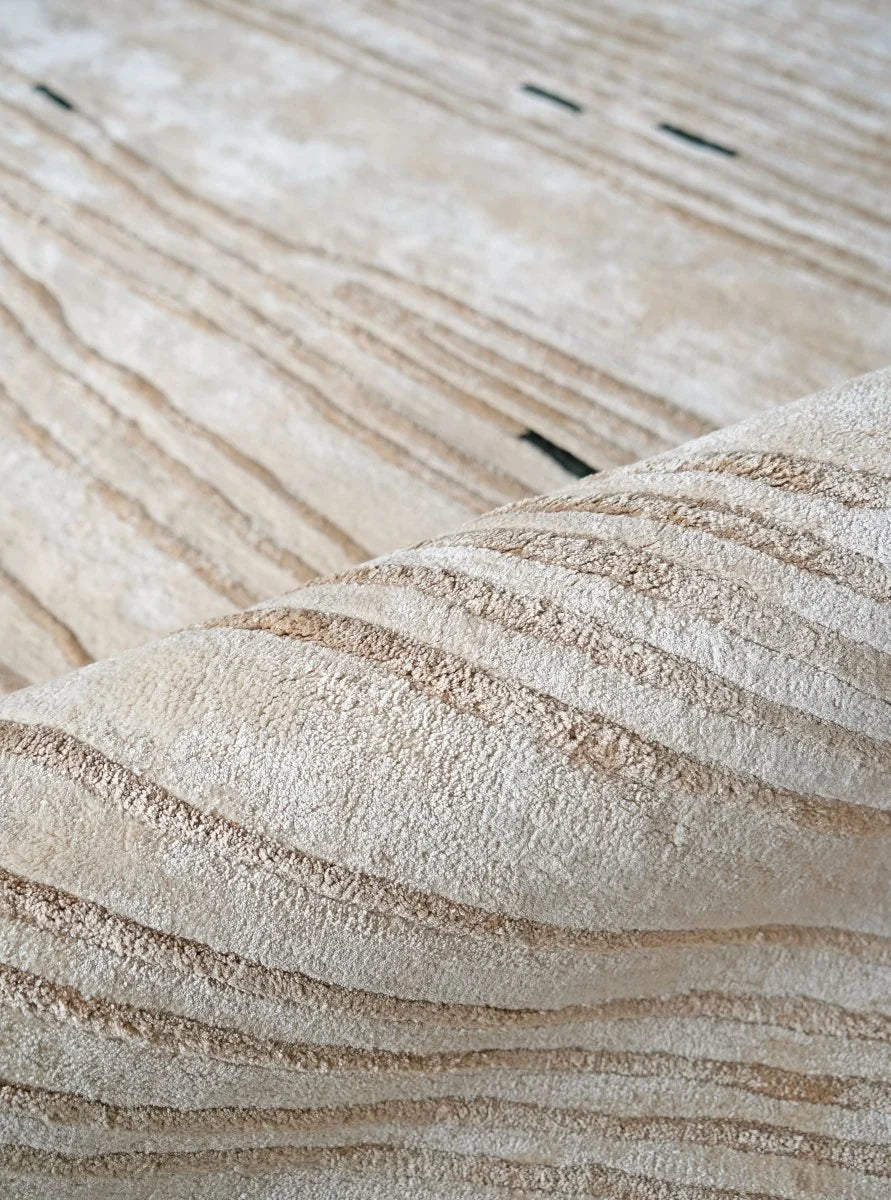 Close-up of a plush, textured area rug with a wavy, layered pattern in warm beige and cream tones.