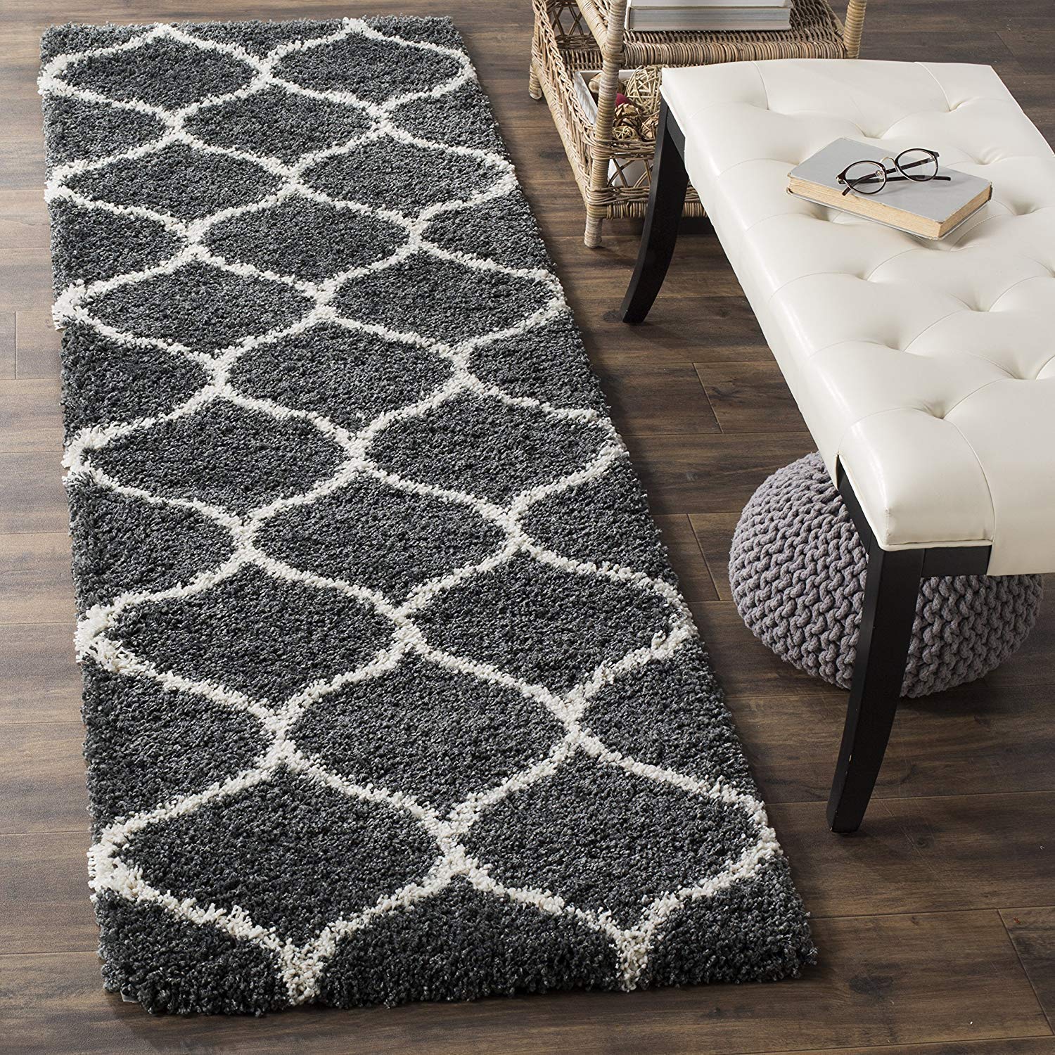 Gray patterned rug on a wooden floor with a white bench and textured stool.