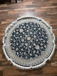 Full overhead view of the Fawaniya round rug featuring a navy field, intricate floral motifs, ornate border, and ivory fringe.