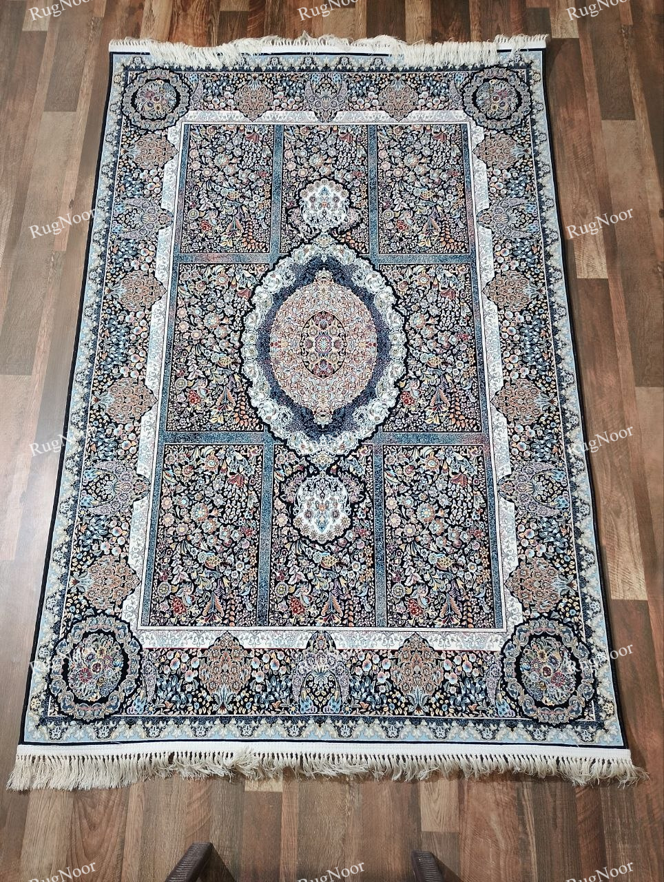Full view of the Shabrang carpet with a deep black ground, ornate central medallion, multicolour floral panels, ivory border, and fringe.