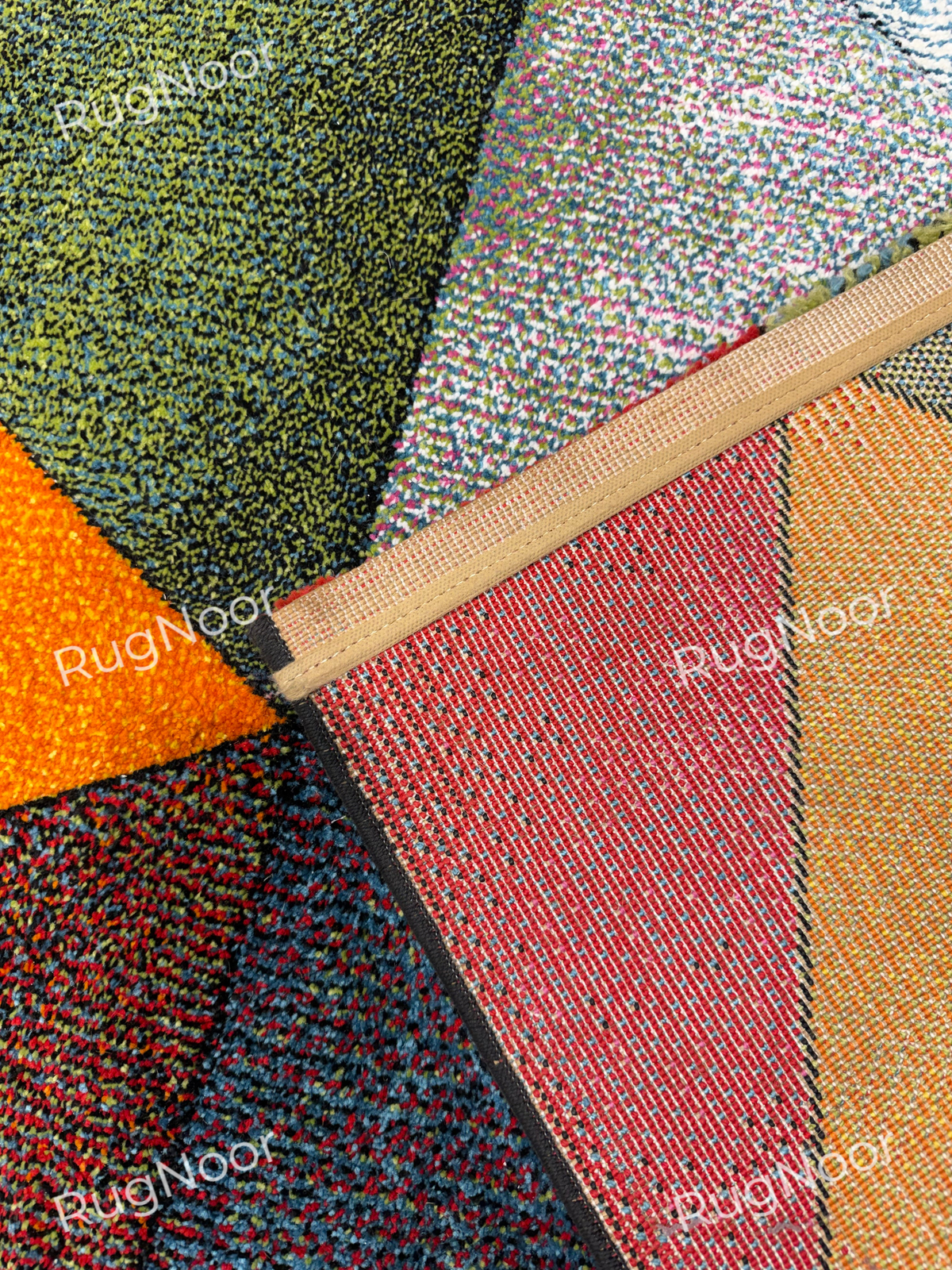 Underside of the Prismland carpet showing its woven backing, bound edge, and the reverse of the coloured triangular design. 