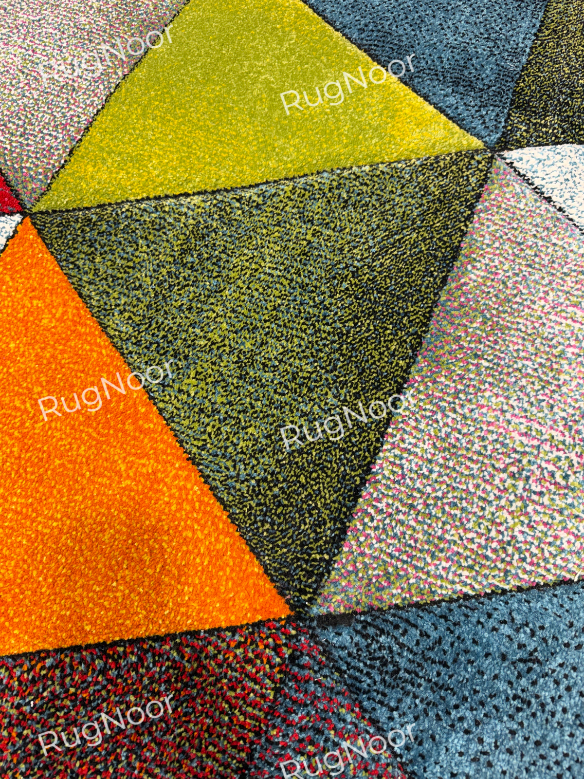 Close-up of the Prismland carpet’s olive, ivory, orange, teal, and multicoloured triangular sections with visible textured pile. 