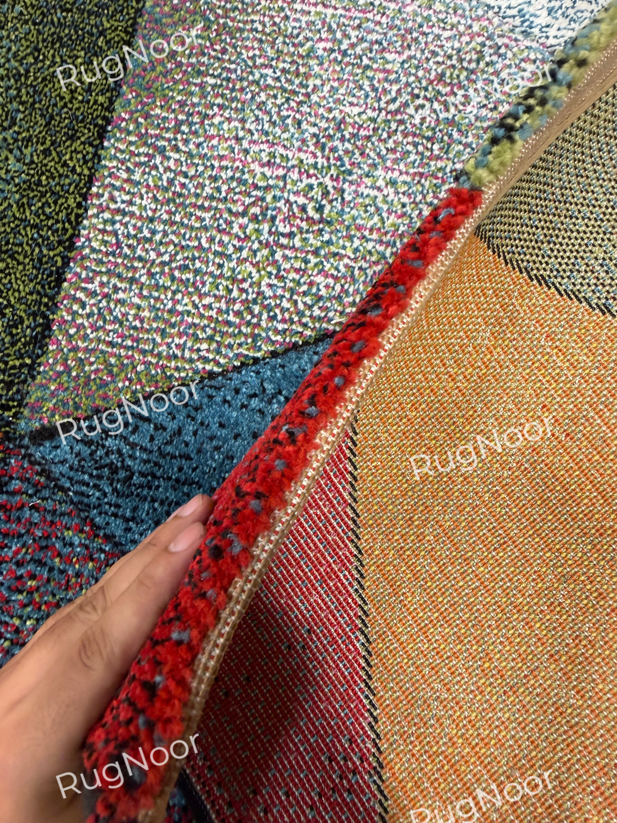 Close-up of the red geometric corner of the Prismland carpet, highlighting the rounded bound edge and underside finish. 