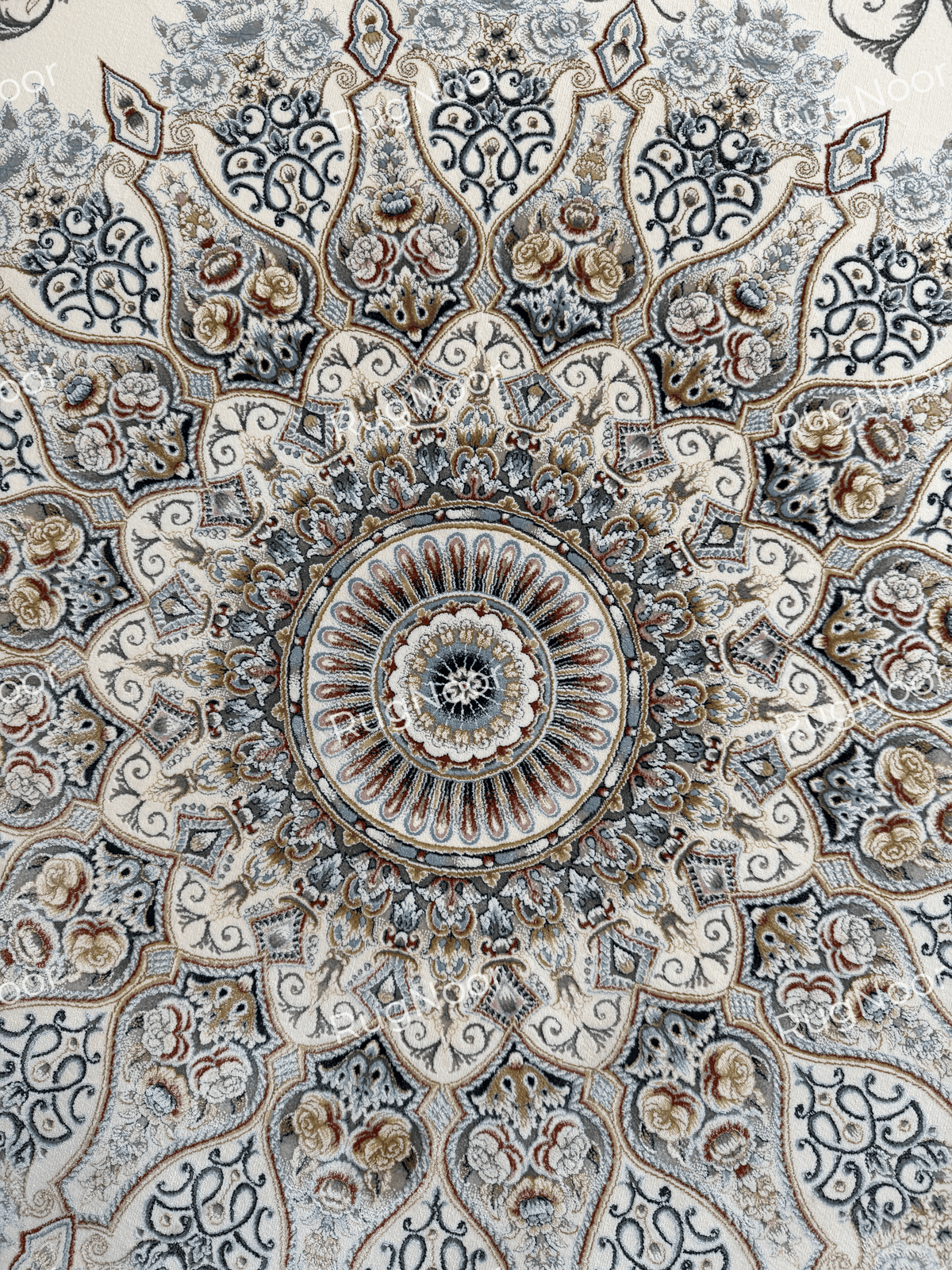 Detailed view of the Mahzarin carpet’s central floral medallion with symmetrical blue-grey, ivory, taupe, and rust-accented motifs.