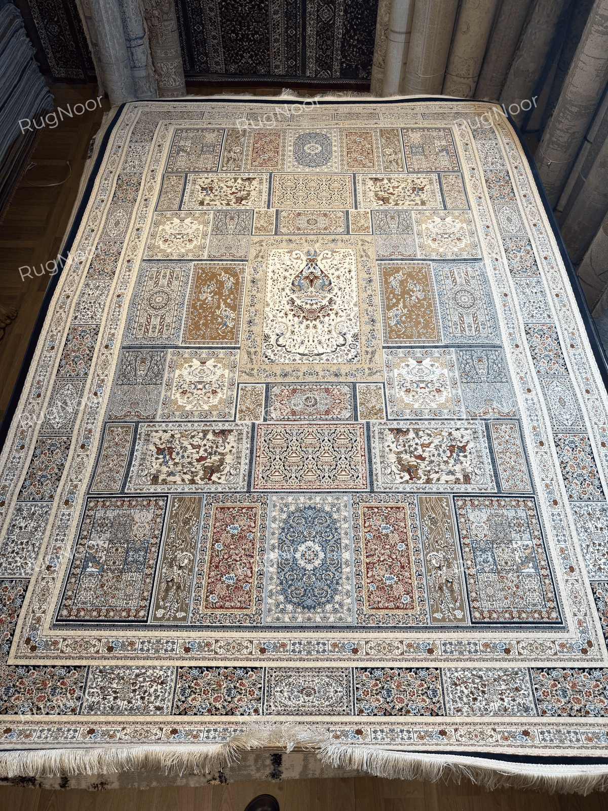 Complete view of the Arghavan carpet showing the ivory central panel, antique-gold sections, dusty-blue accents, burgundy motifs, and decorative outer border.