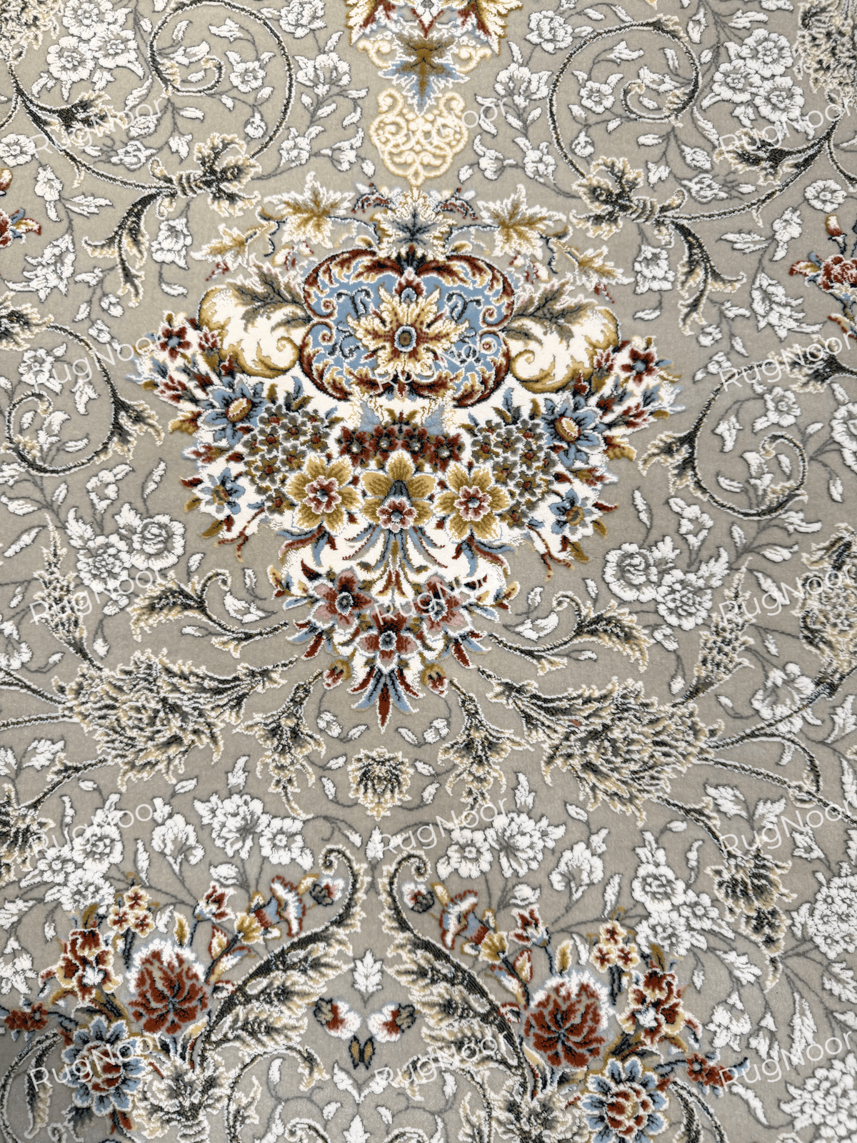 Close-up of the ornate ivory floral medallion and surrounding motifs on Zanbaq's grey carpet field, RugNoor.