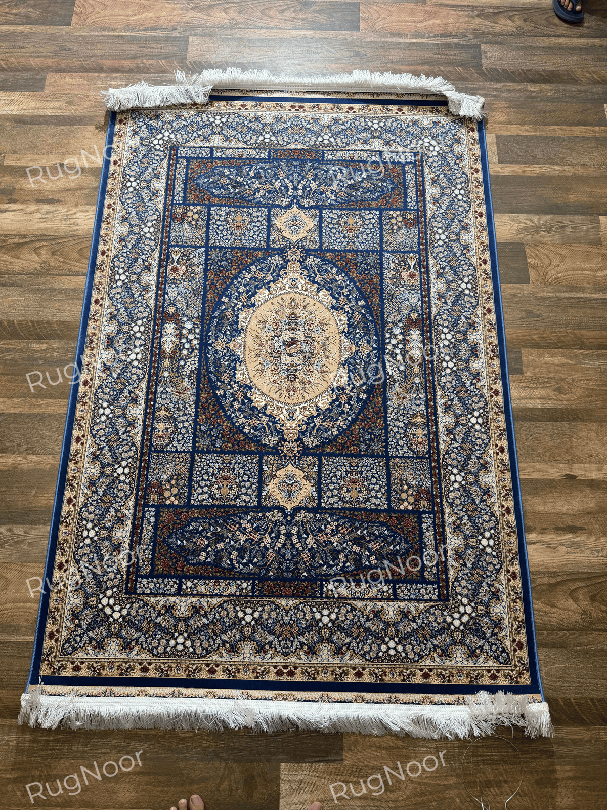 Full view of Nayrizan's navy blue carpet with an oval floral medallion and layered borders.